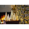 Decorative Christmas trees on a table with a blurred festive background