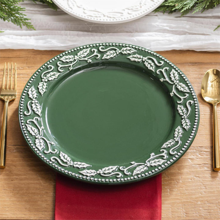 Green plate with decorative white patterns on a wooden table with gold cutlery and a red napkin.