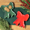 Green and red bow-shaped plates with cookies on a green cloth and wooden surface.