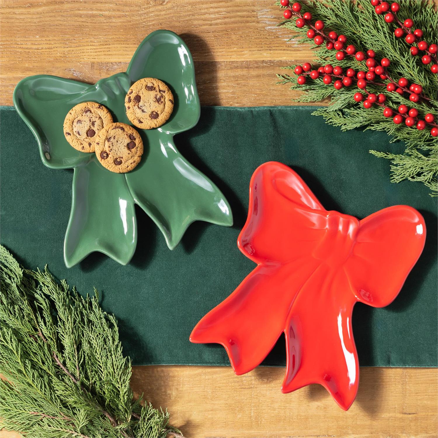 Green and red bow-shaped plates with cookies on a green cloth and wooden surface.