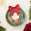 Wreathe shaped serving plate with a red bow, featuring two cookies on a white background.