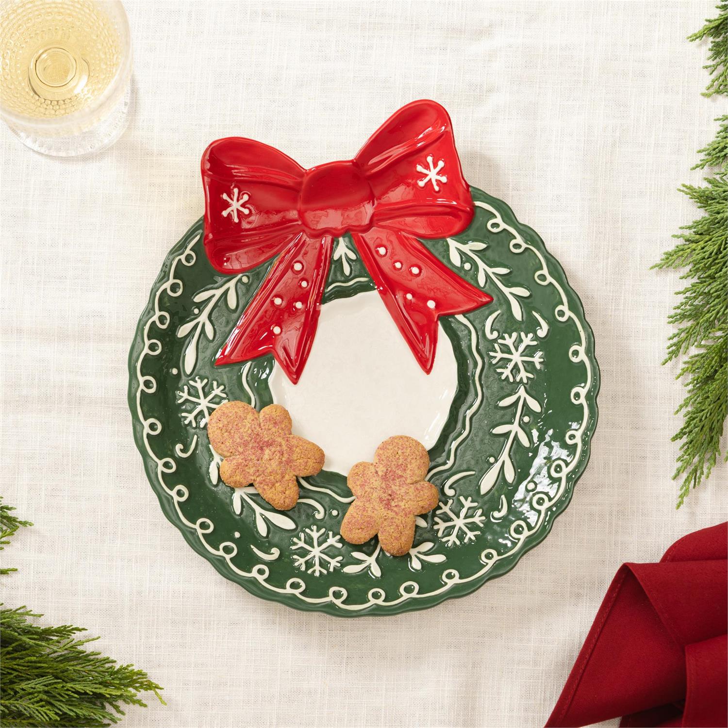 Wreathe shaped serving plate with a red bow, featuring two cookies on a white background.