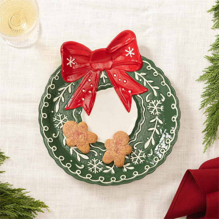 Wreathe shaped serving plate with a red bow, featuring two cookies on a white background.