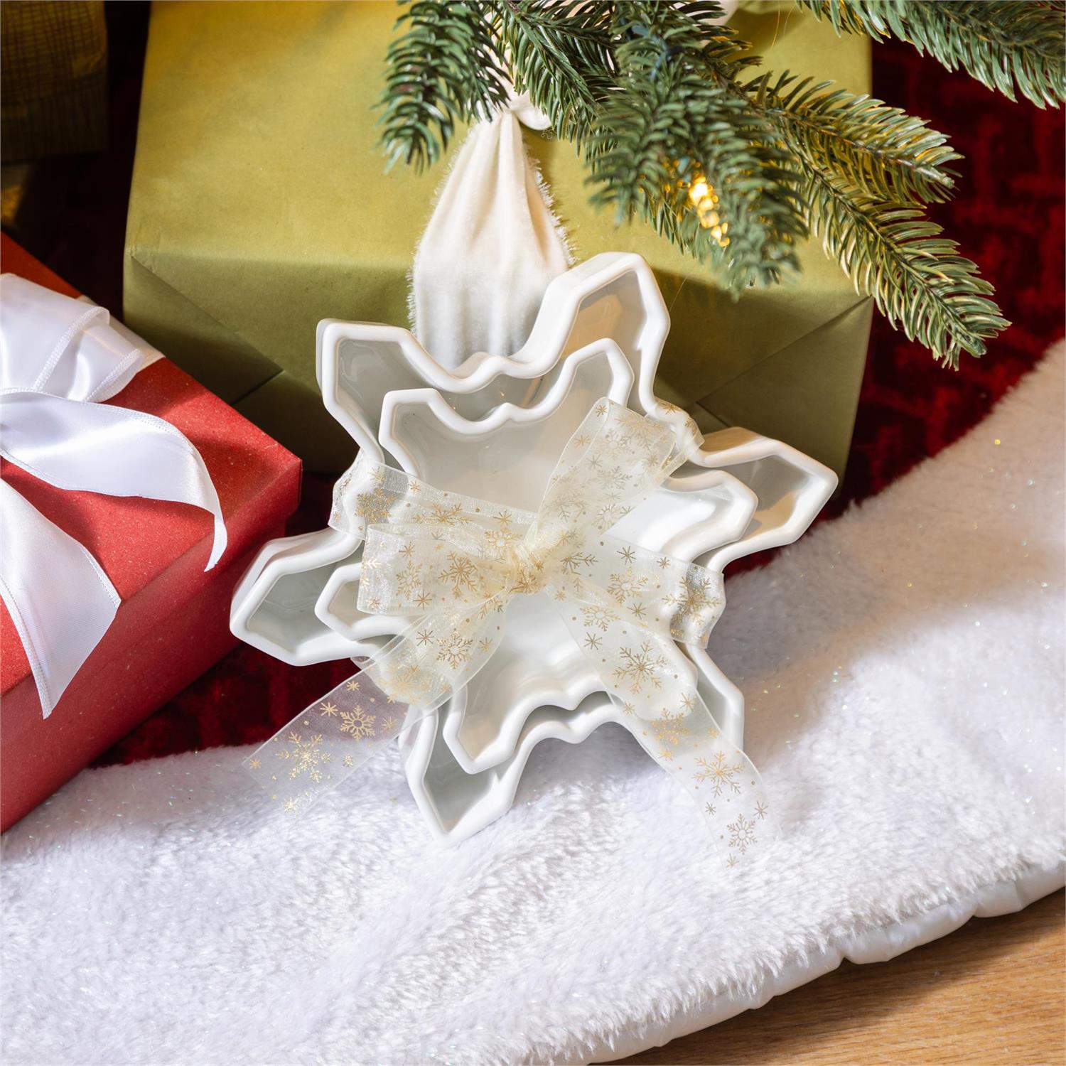 Decorative snowflake-shaped dishes on a Christmas tree with presents underneath