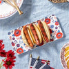 Hot dogs on a floral plate with red and blue flowers.