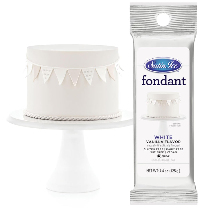 White cake with decorative elements and a package of Satin Ice fondant on a white background