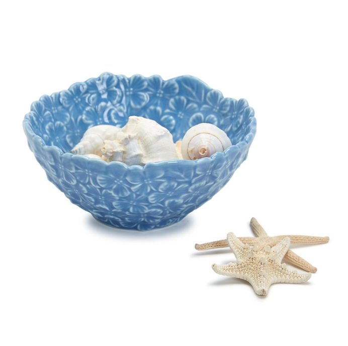 Blue decorative bowl in floral pattern with seashells and starfish on a white background