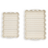 Two beige scalloped placemats on a white background