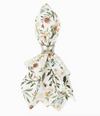 A cloth napkin with floral and greenery design in a silver napkin ring on a white background
