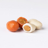 Four round candies, two orange and two white, with an almond in the middle on a white background.