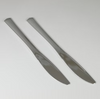 Two silver knives on a light gray background