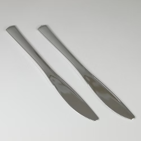 Two silver knives on a light gray background