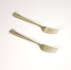 Two gold forks on a white background