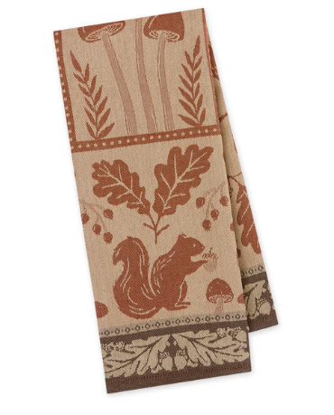 A folded kitchen towel featuring a rustic autumn forest pattern with a squirrel, oak leaves, acorns, and mushrooms in terracotta and brown on a beige background.