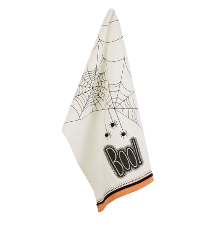 An off-white Halloween-themed napkin featuring a black spiderweb pattern, small spiders, the word 'BOO!' in a comic-style font, and an orange border along the bottom edge.