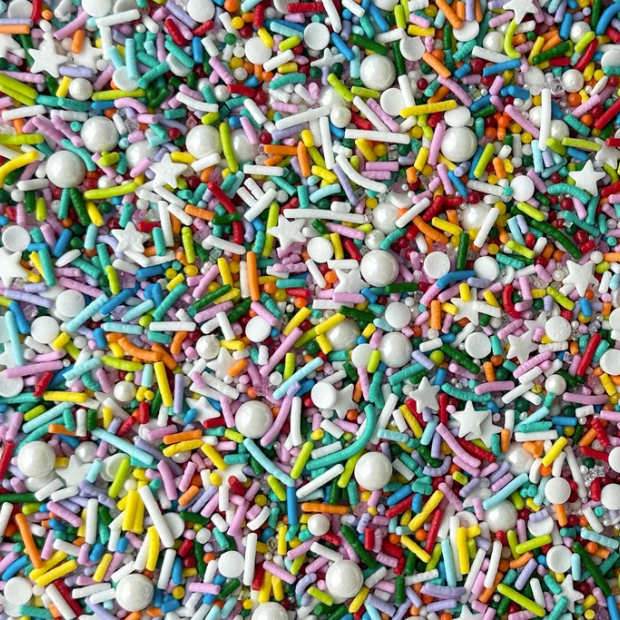 A close-up view of colorful sprinkles, including white round pearls, white star-shaped sprinkles, and multi-colored jimmies in pink, blue, green, yellow, orange, and red.