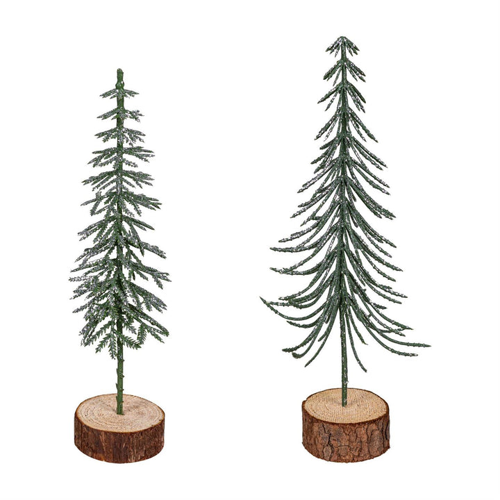 Two miniature Christmas trees on wooden bases against a white background