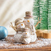 Decorative snowman family figurine with a Christmas tree in the background