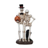 Skeleton couple figurine holding a pumpkin on a white background