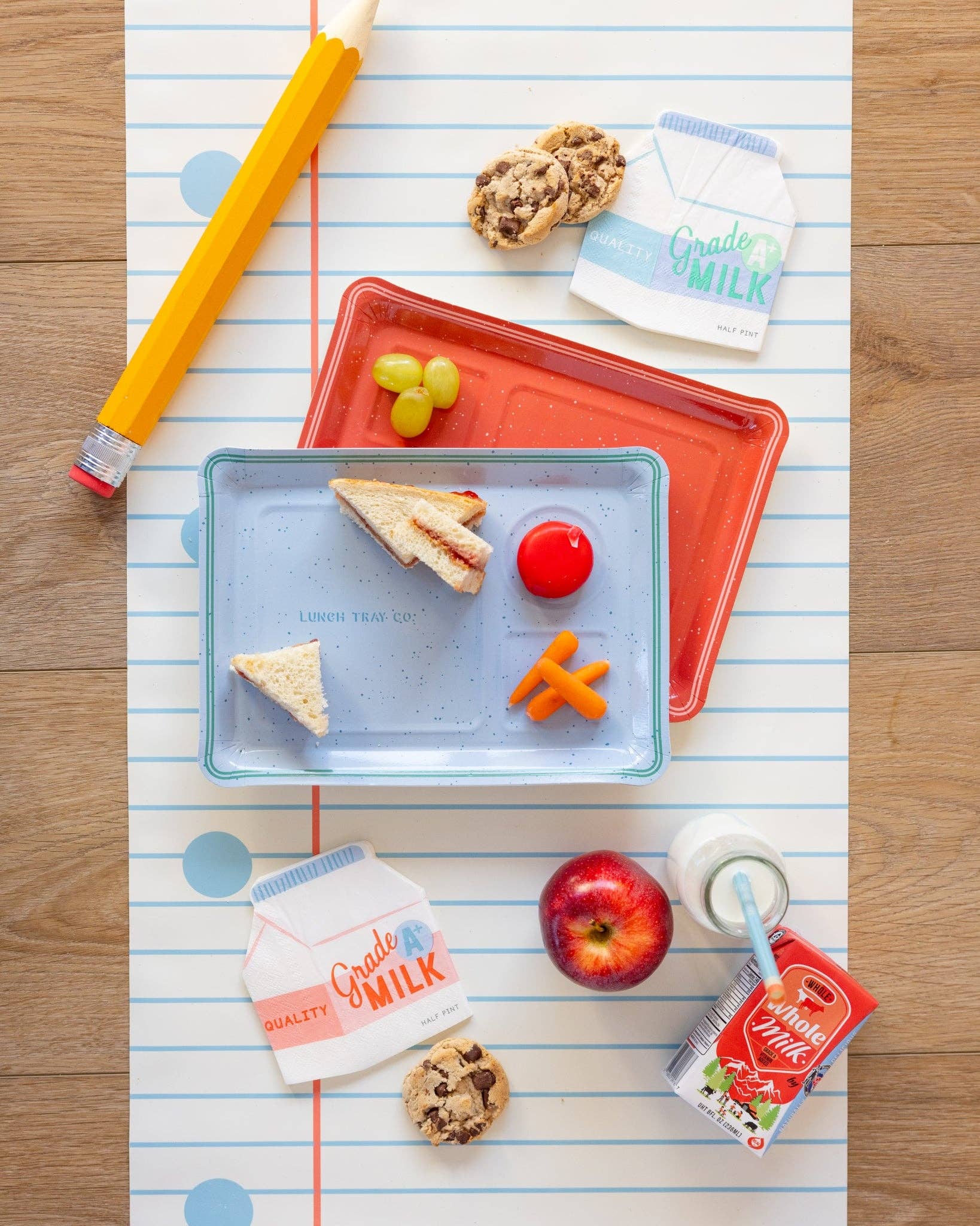 School lunch setup with tray, sandwich, fruit, and milk on a paper background