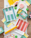 Colorful notebook plates with striped designs on a wooden surface with small decorative items.