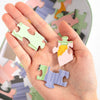 Hand holding colorful puzzle pieces with a partially assembled puzzle in the background