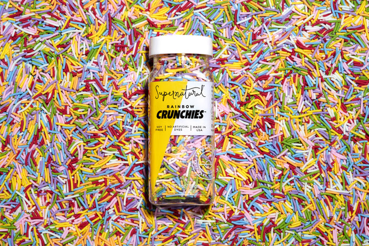 Supernatural Rainbow Crunchies jar on a colorful sprinkles background
