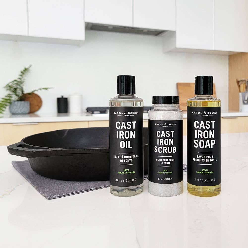 Three bottles of Cast Iron Care products on a kitchen counter with a cast iron skillet.
