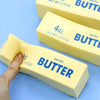 Three bars of salted butter squish toys with a hand touching one of them on a blue background