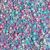 Colorful sprinkles mix with blue, pink, and white in a close-up shot.