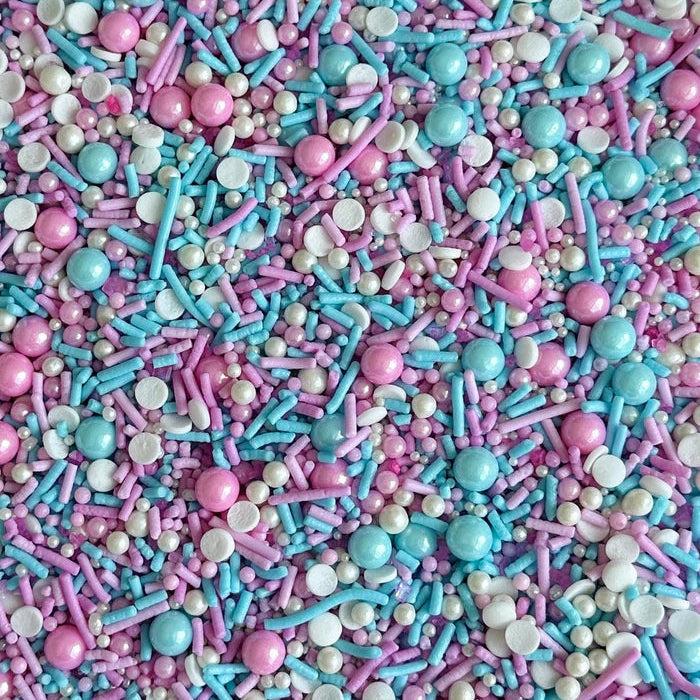 Colorful sprinkles mix with blue, pink, and white in a close-up shot.