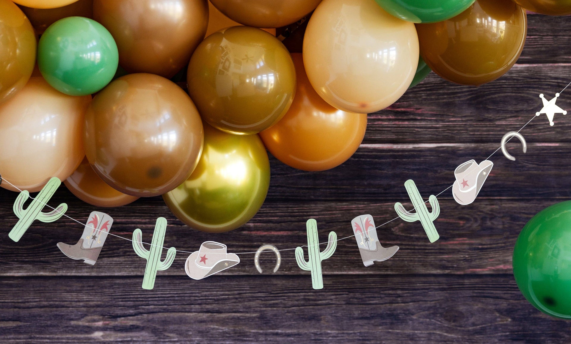 Colorful balloons and a decorative banner with cactus shapes on a wooden surface