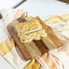 Loaf of bread sliced on a wooden serving board with a striped cloth underneath