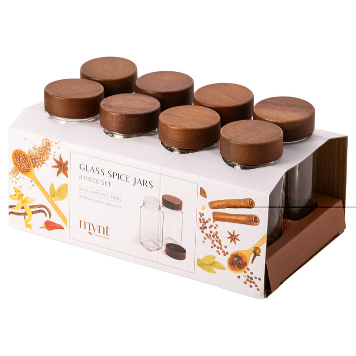 Set of glass spice jars with wooden lids in packaging on a white background