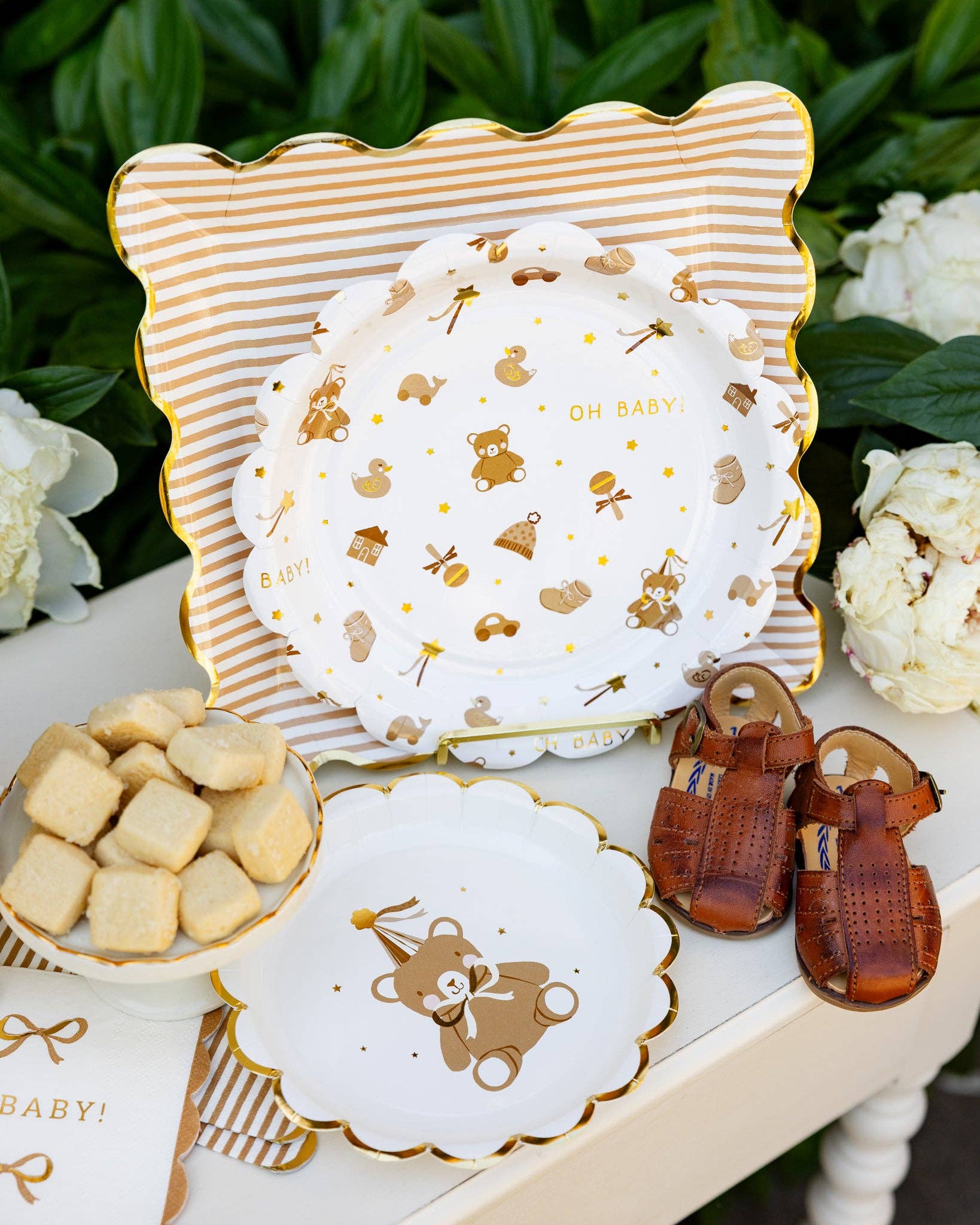 Decorative baby plates with gold bear designs on a white surface with greenery in the background.