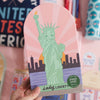 Puzzle with a green statue of liberty design on a pink background, held by a hand.