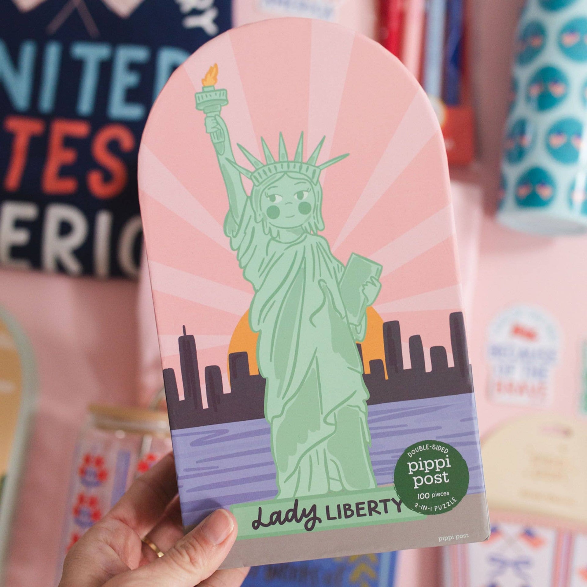 Puzzle with a green statue of liberty design on a pink background, held by a hand.