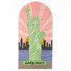 Jigsaw puzzle with a design of the Statue of Liberty against a pink sky and city skyline.
