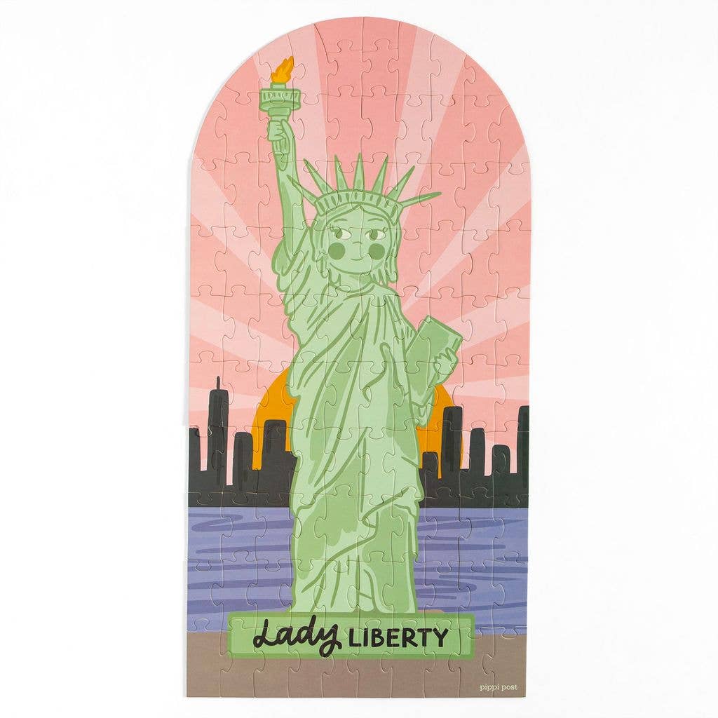 Jigsaw puzzle with a design of the Statue of Liberty against a pink sky and city skyline.