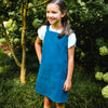 Young girl wearing a blue apron standing in a garden