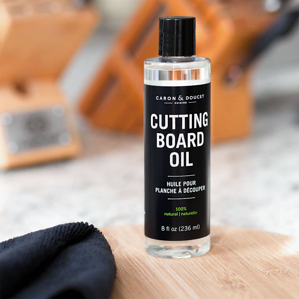 Bottle of Caron & Doucet cutting board oil on a wooden surface with a blurred background
