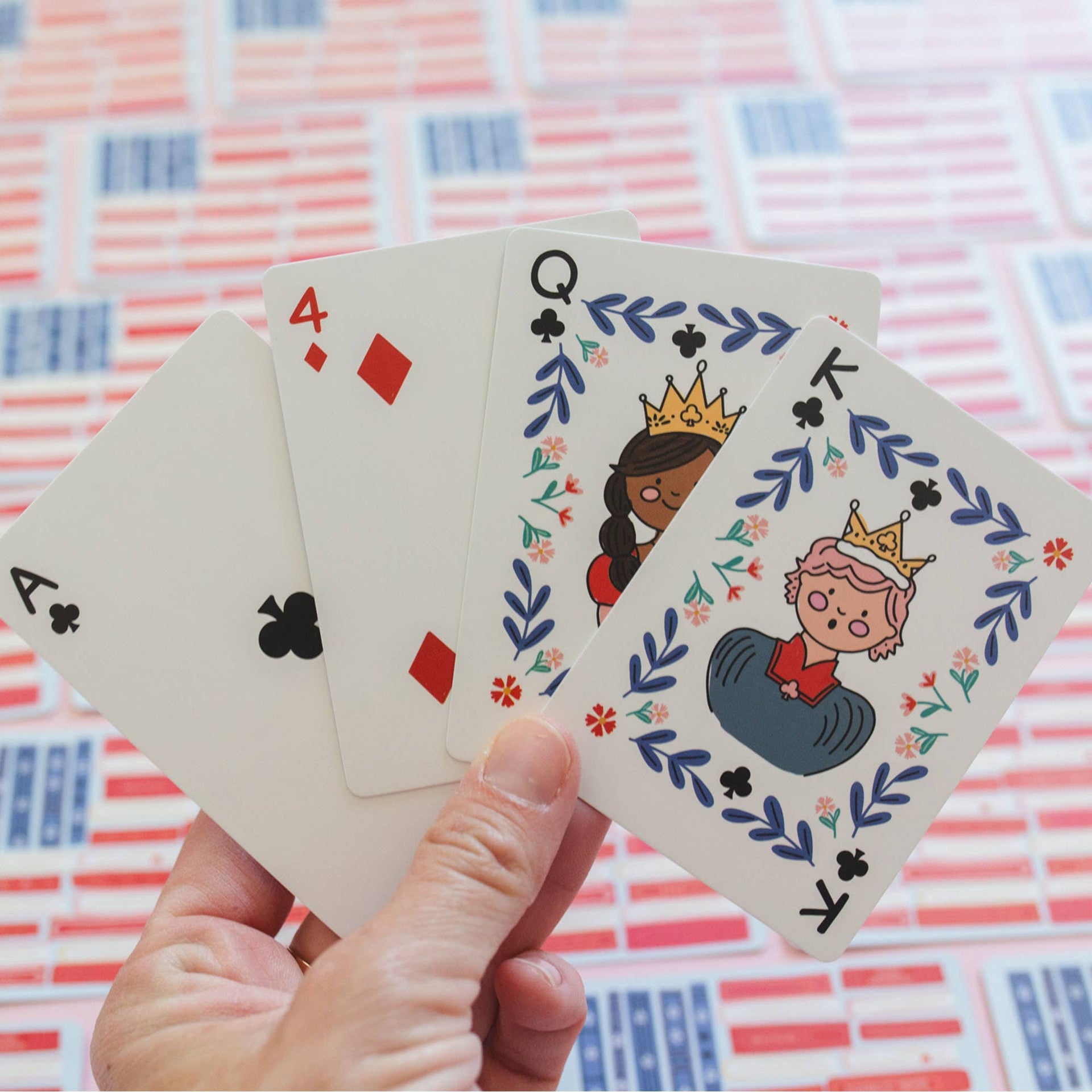 Hand holding playing cards with decorative designs on a patterned background