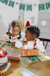 Two children sitting at a table with educational materials and a 'Back to School' banner in the background.
