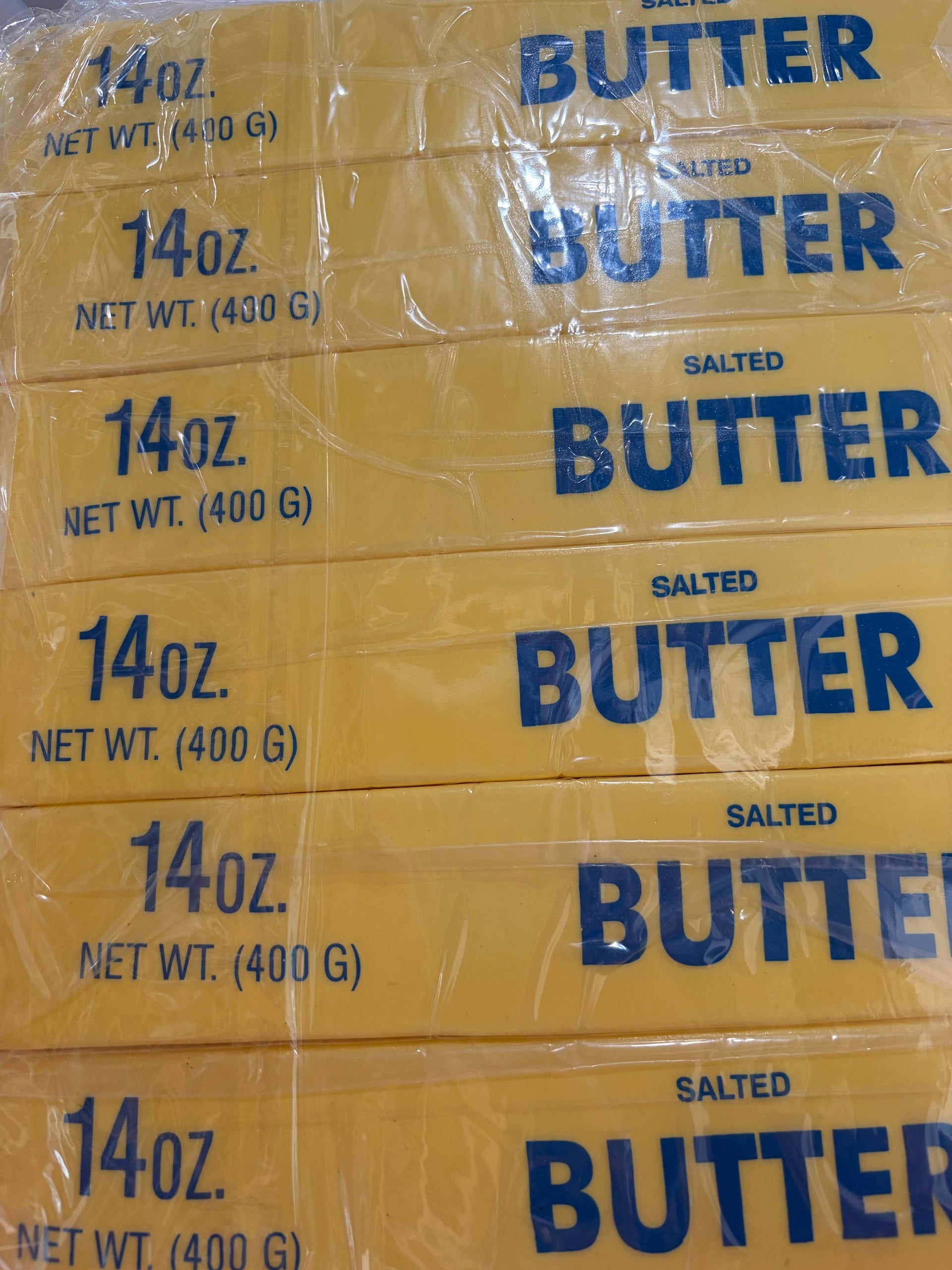 Stack of yellow butter squishy toy packages with blue text