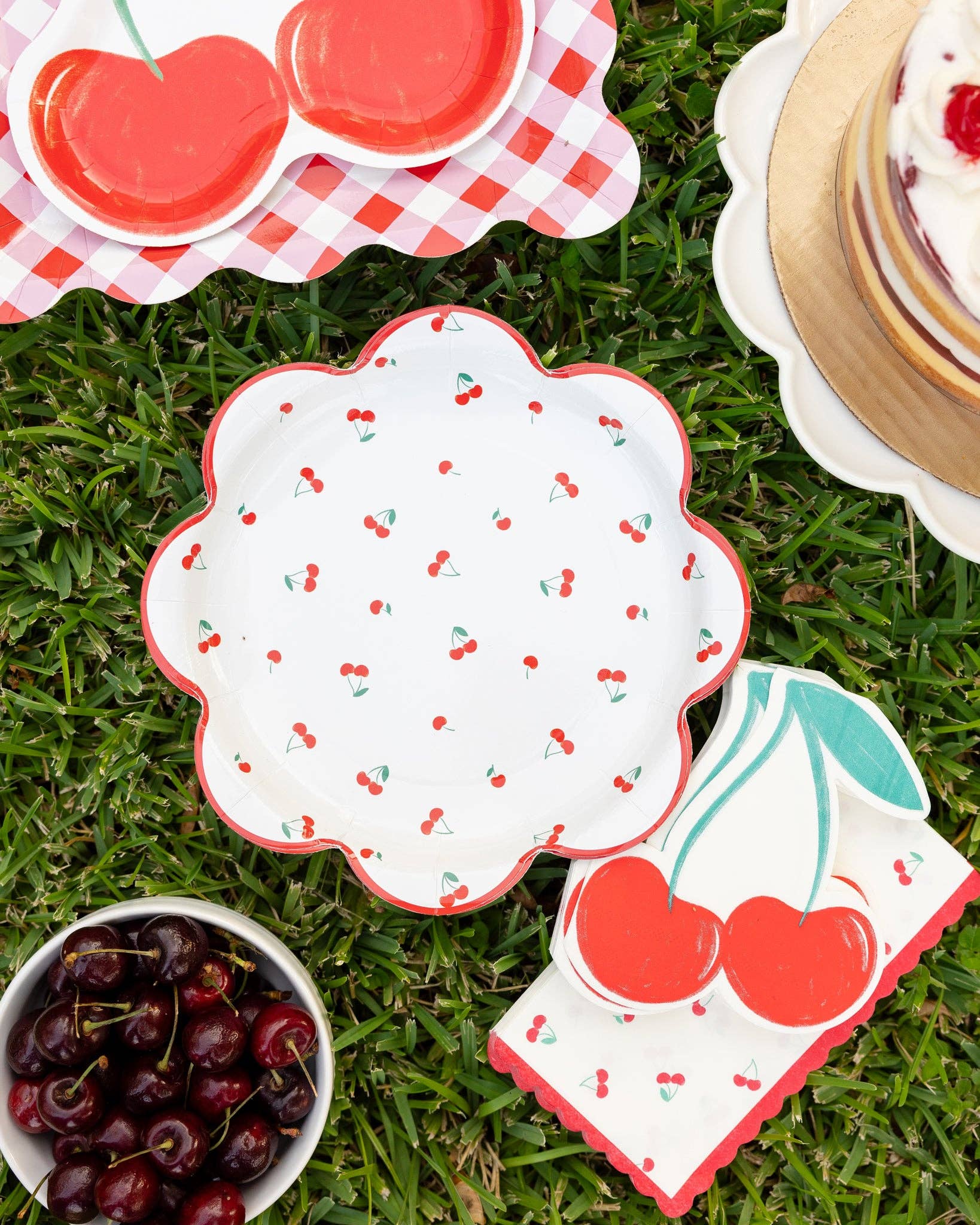 Cherry-themed plates, napkins, and bowls on grass