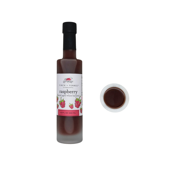 Bottle of raspberry barrel aged balsamic vinegar with a label on a white background