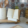 Open book on a marble stand with a tiled wall in the background