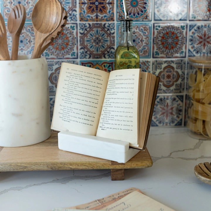 Open book on a marble stand with a tiled wall in the background