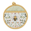 Round pot holder with bee and floral design on a white background