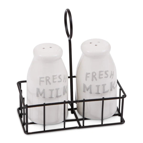 Two white milk bottle salt and pepper shakers labeled 'Fresh Milk' in a black metal stand on a white background